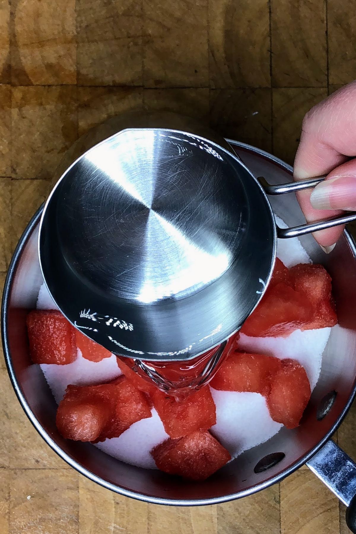 Pouring water into a pot with watermelon.