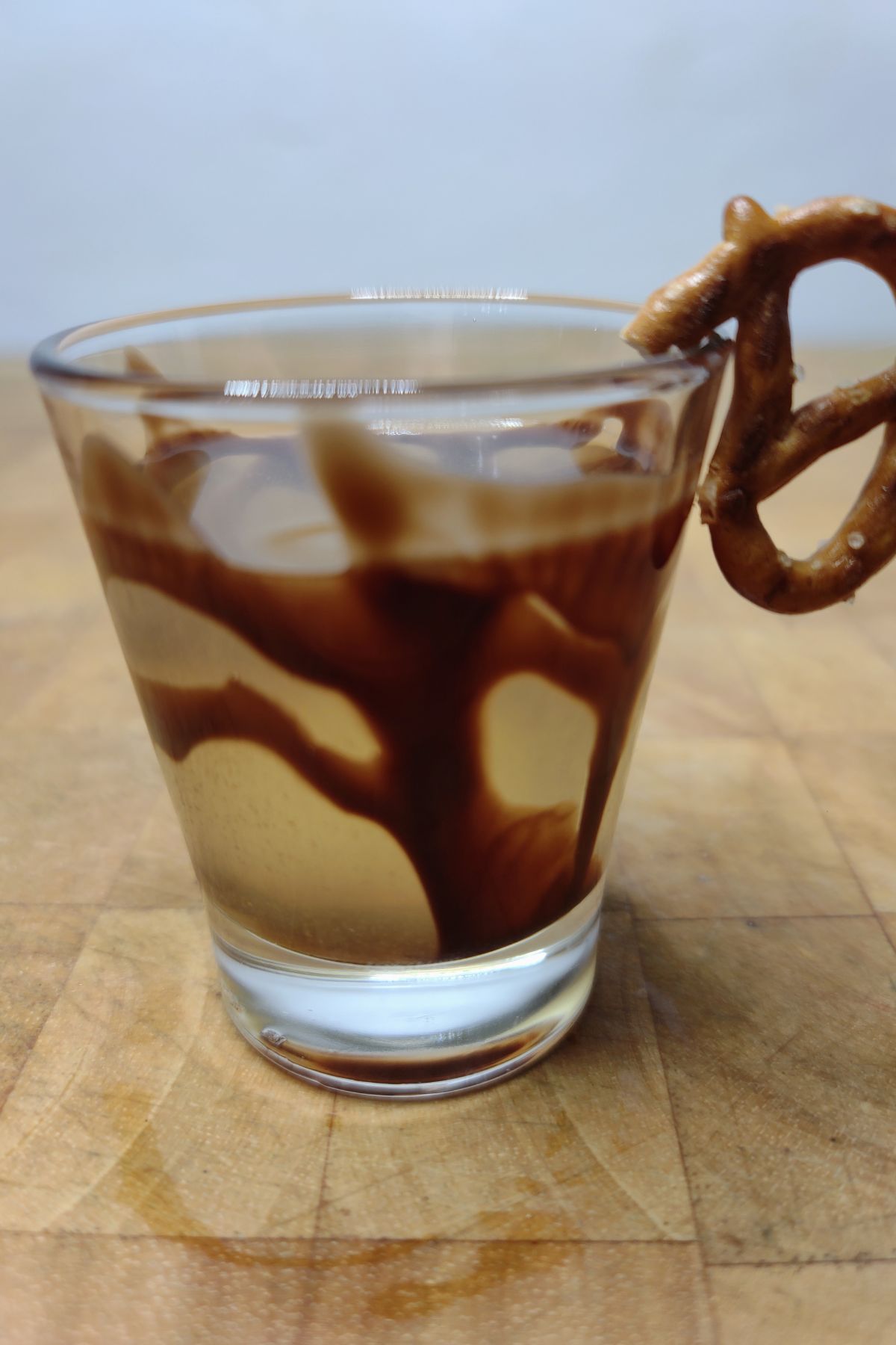 Chocolate covered pretzel shot on a wooden table.