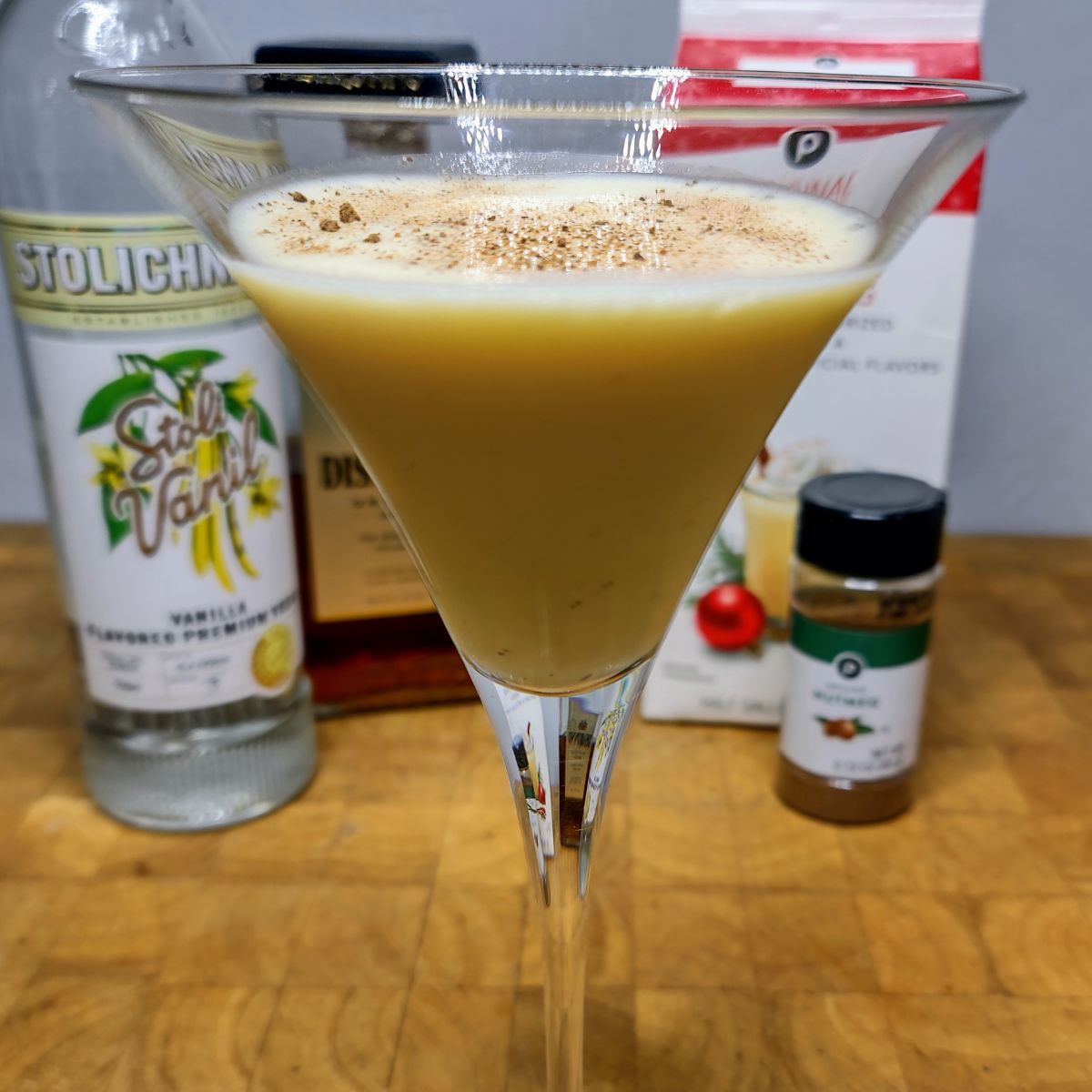 Closeup of eggnog martini with ingredients in background.