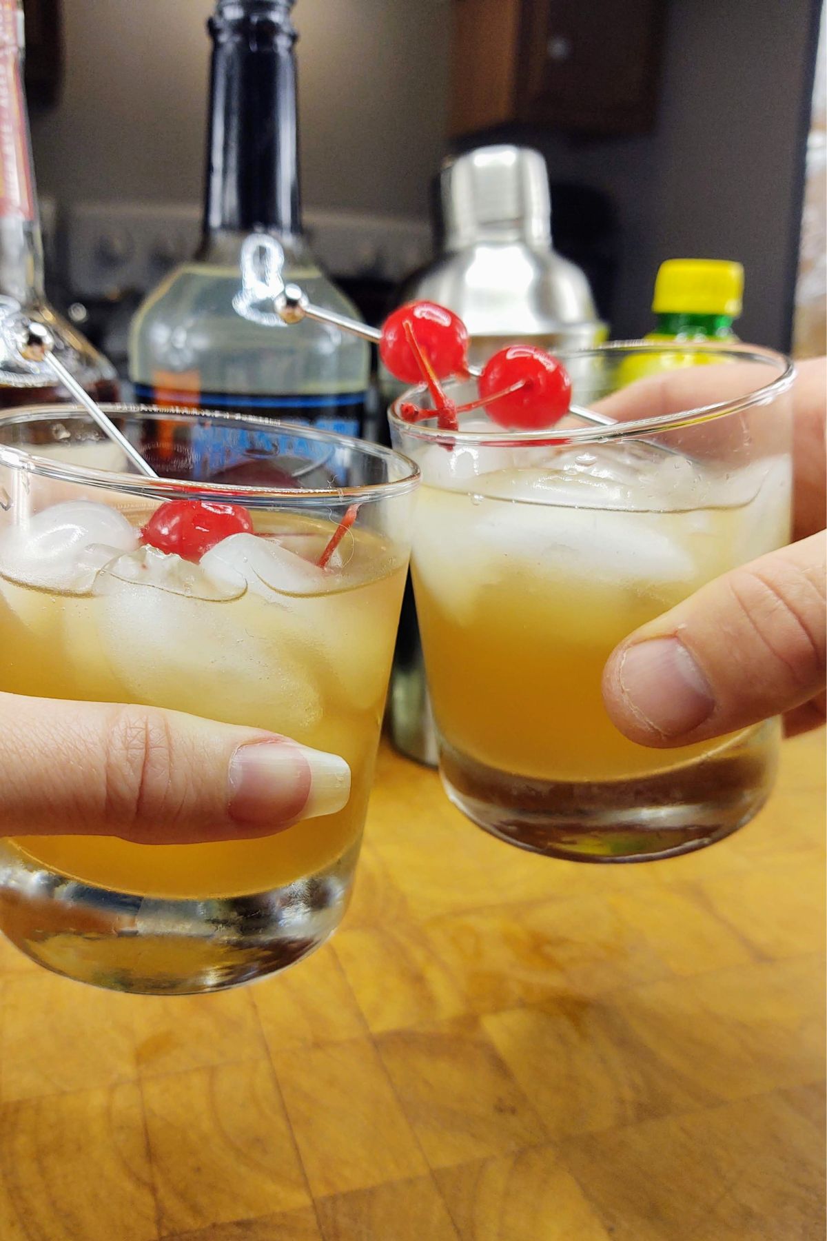 Clinking two whiskey sours together.
