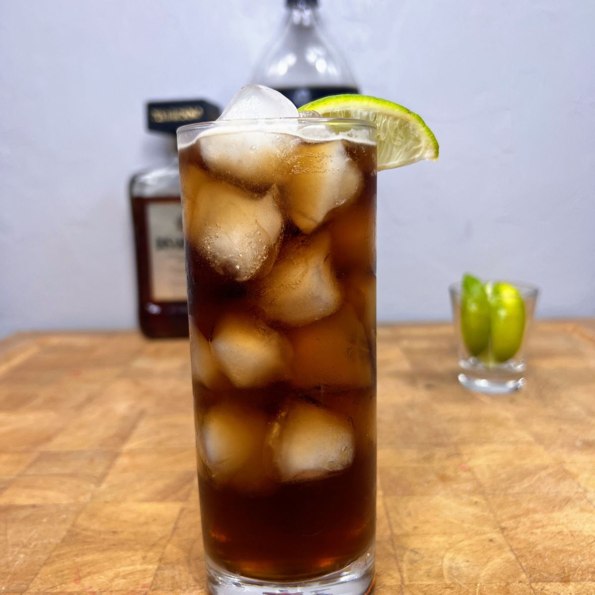 Close up of an amaretto and coke with a lime wedge on the rim.