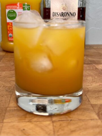 Amaretto and orange juice on a wooden table.