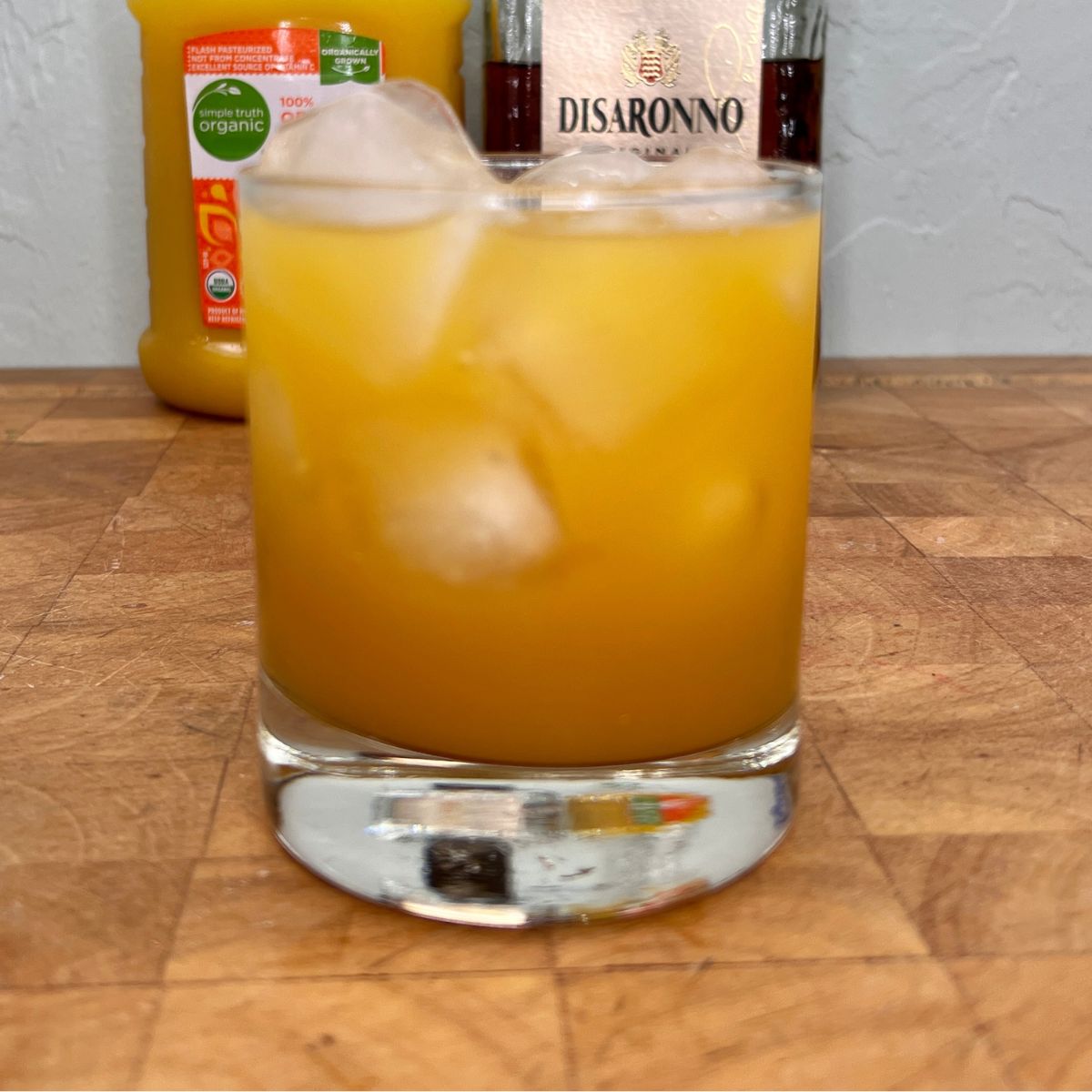 Amaretto and orange juice on a wooden table.