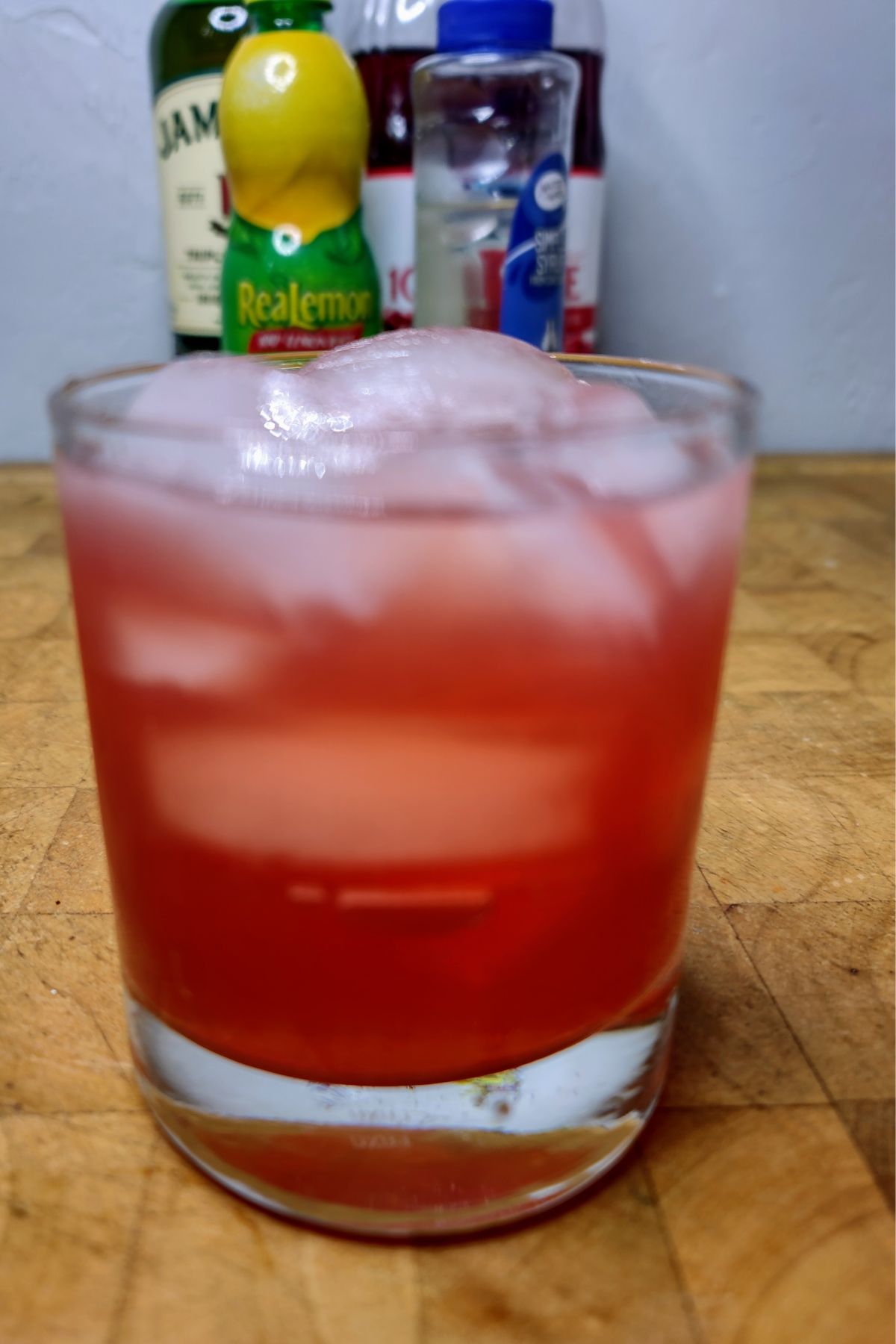 Cranberry whiskey sour on a wooden table.