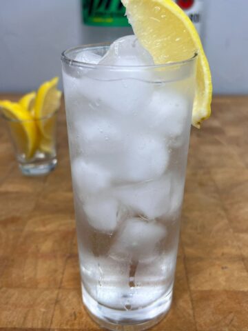 Close up of a rum and sprite with a lemon wedge on the rim.