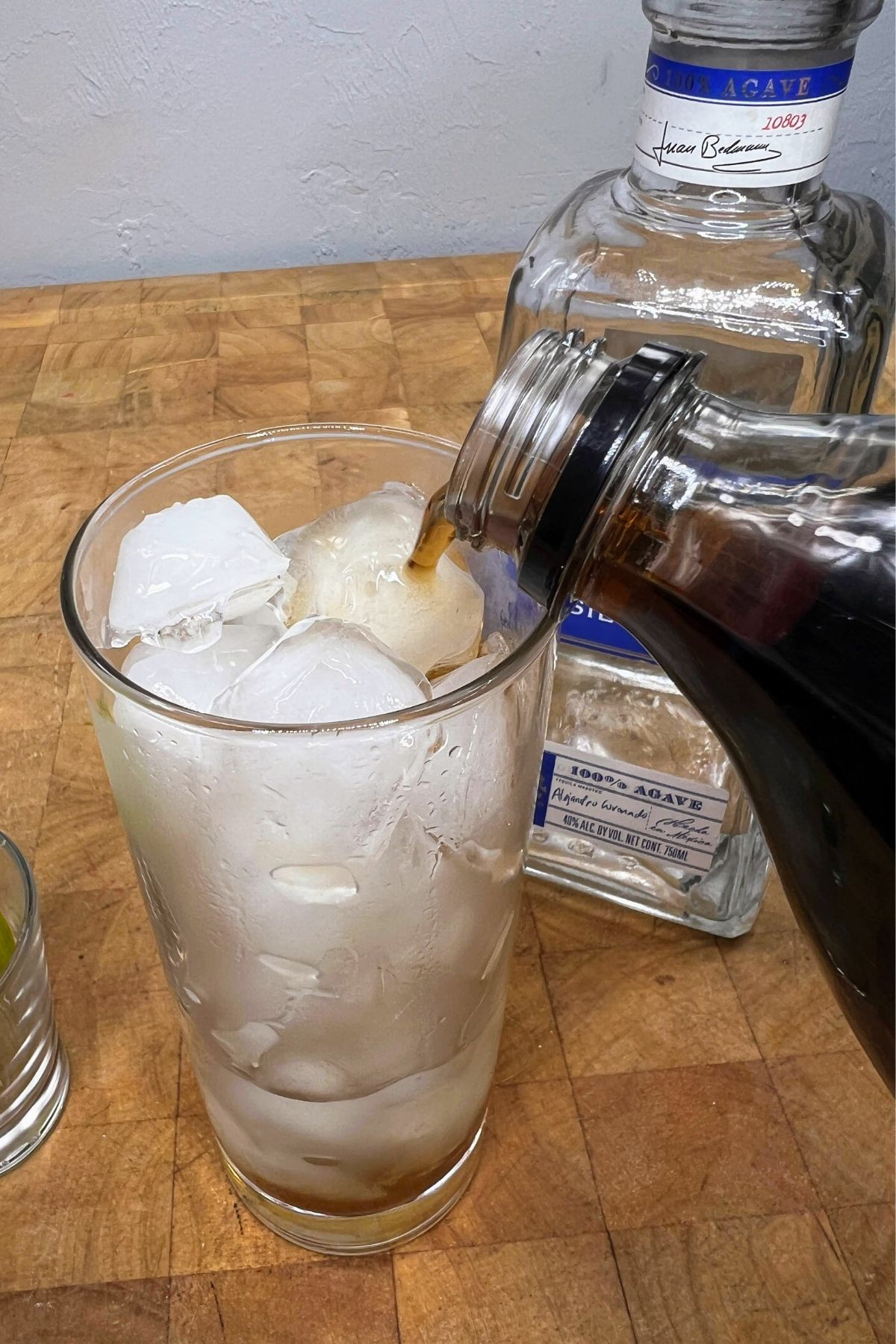 Pouring coke into a highball glass with tequila.