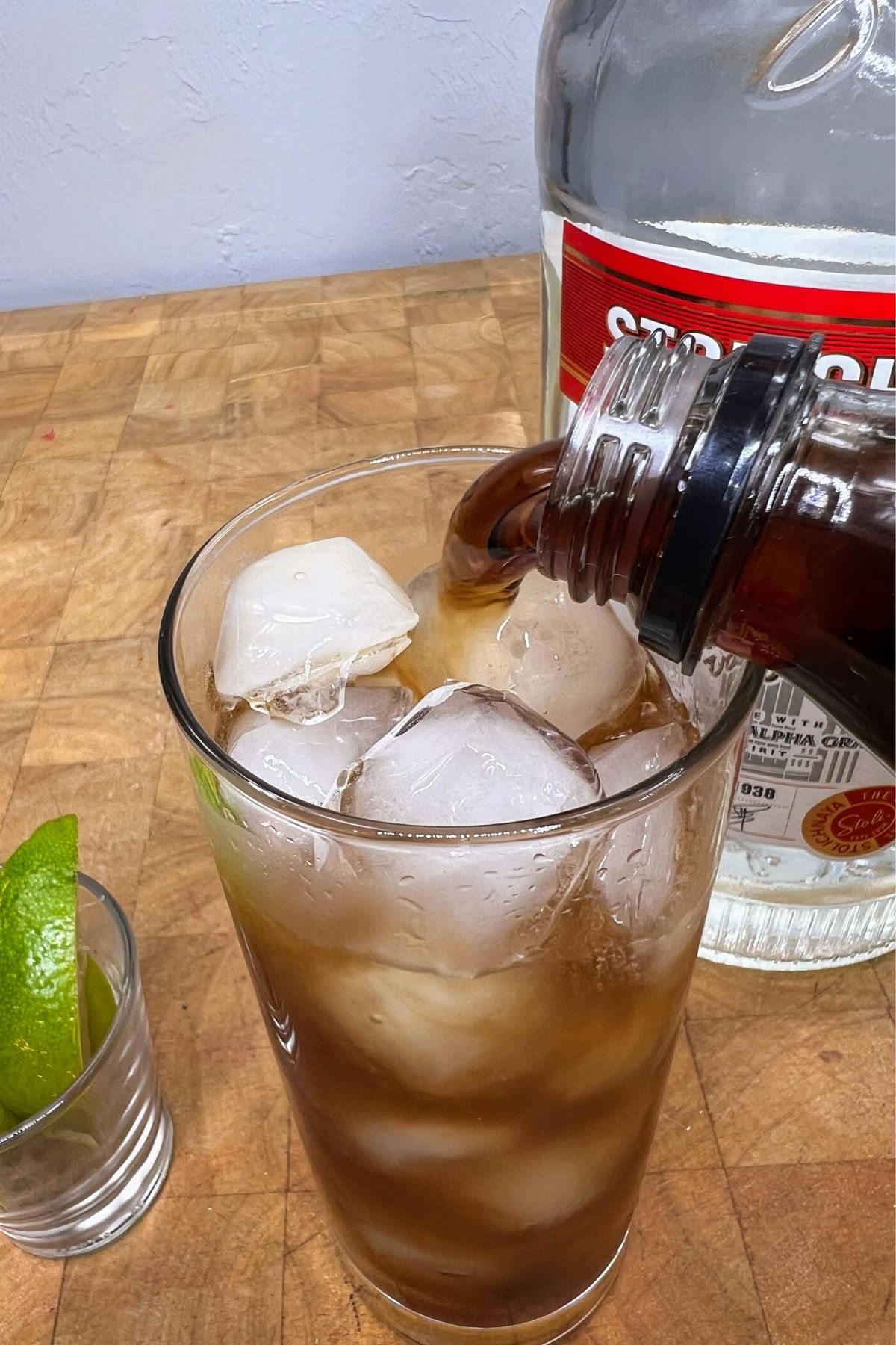 Pouring coke into a highball glass with vodka.