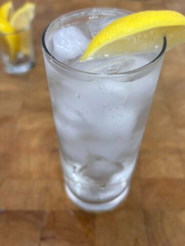 Close up of a vodka sprite in a highball glass with lemon wedge on the rim.
