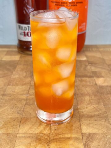 Whiskey and orange soda in a glass on a wooden table.